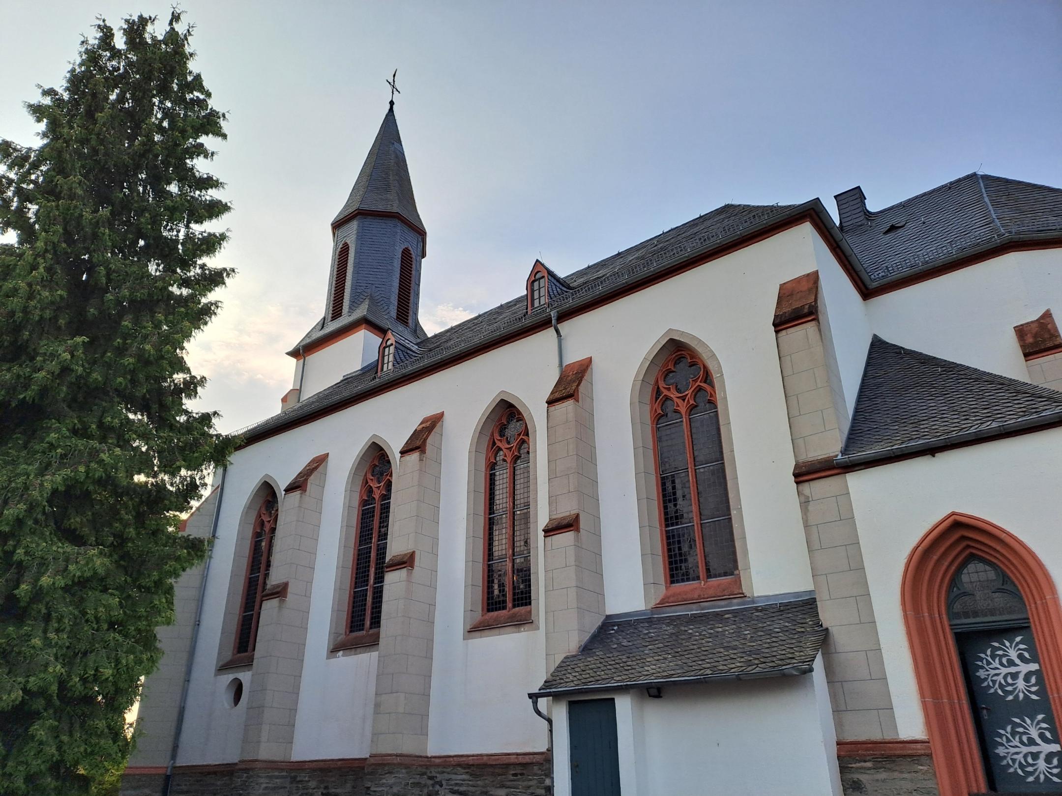 Seitenansicht der Kirche St. Stephanus Laubach mit Spitzbogenfenstern, Strebepfeilern und Kirchturm.