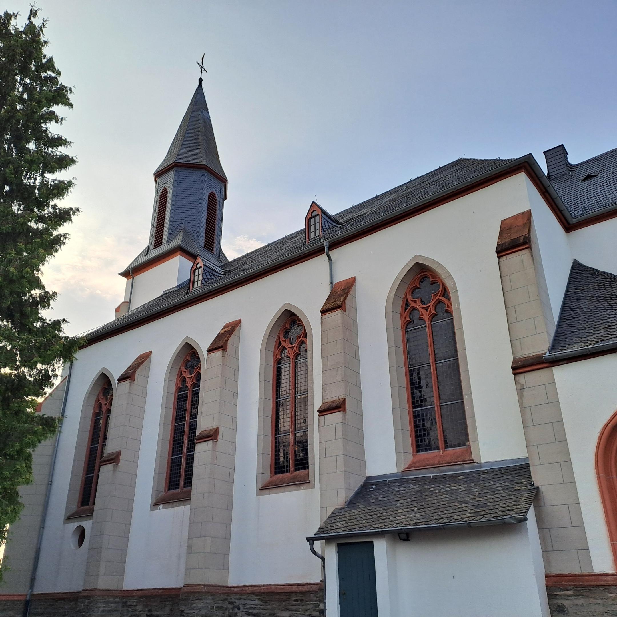 Seitenansicht der Kirche St. Stephanus Laubach mit Spitzbogenfenstern, Strebepfeilern und Kirchturm.