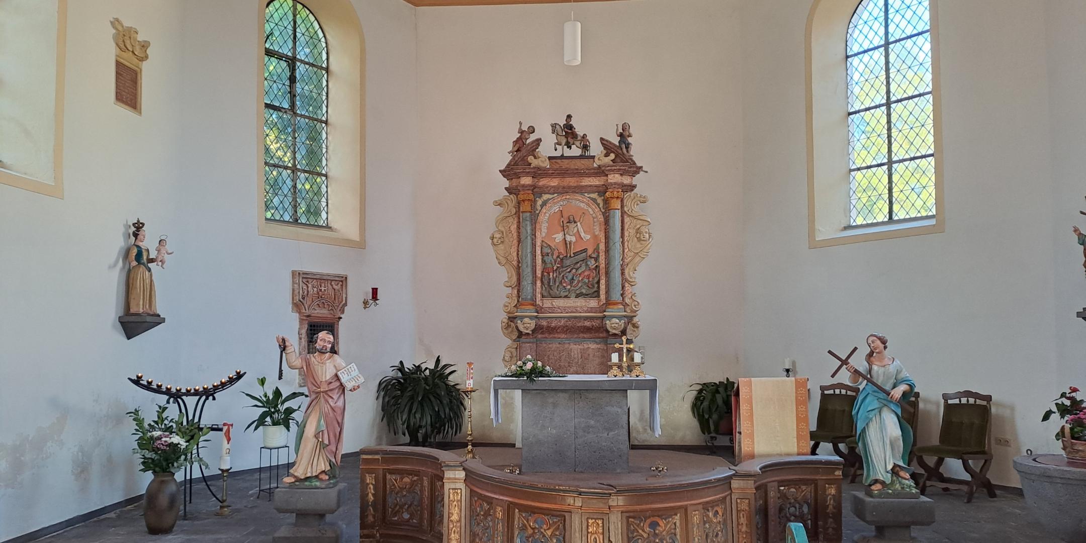 Blick in den Altarraum der Kirche St. Martin mit Altar, Figuren und hohen Fenstern.