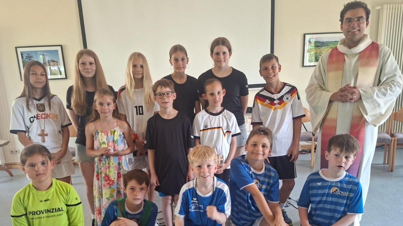 Priester mit zahlreichen Kindern in Sporttrikots