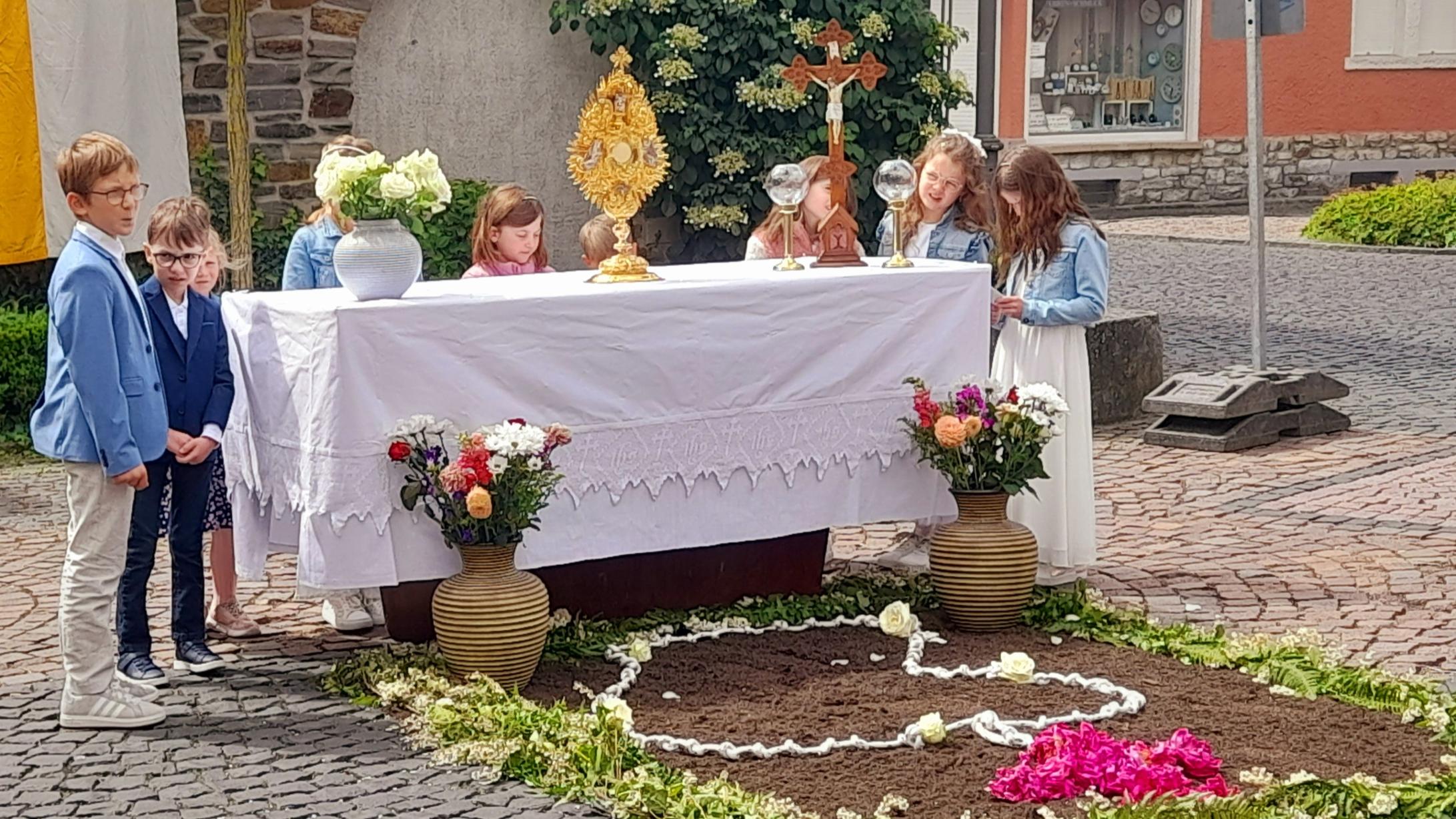 Kinder hinter einem Altartisch im Freien hinter einer Bruchsteinwand