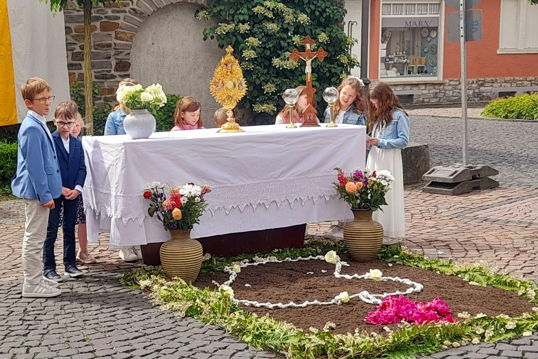 Kinder hinter einem Altartisch im Freien hinter einer Bruchsteinwand