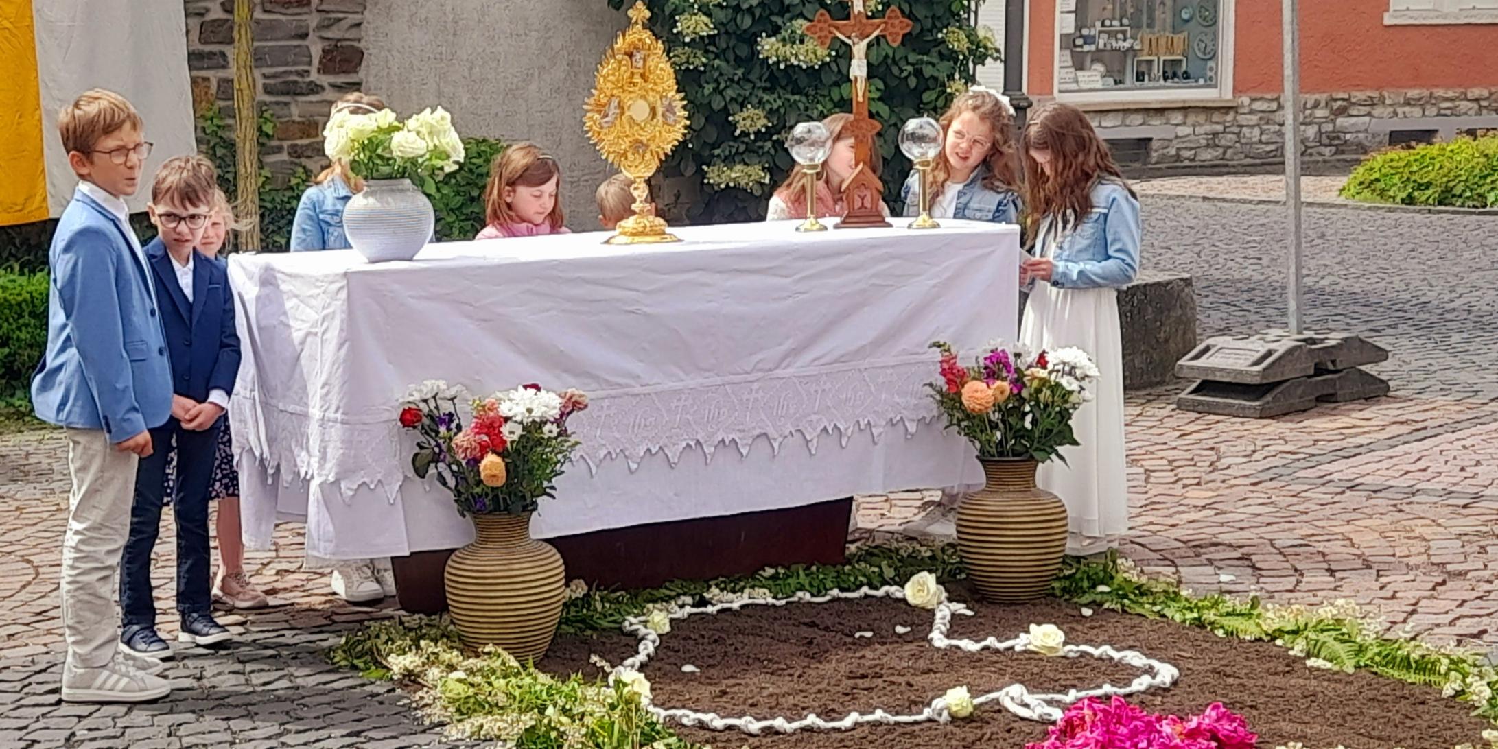 Kinder hinter einem Altartisch im Freien hinter einer Bruchsteinwand
