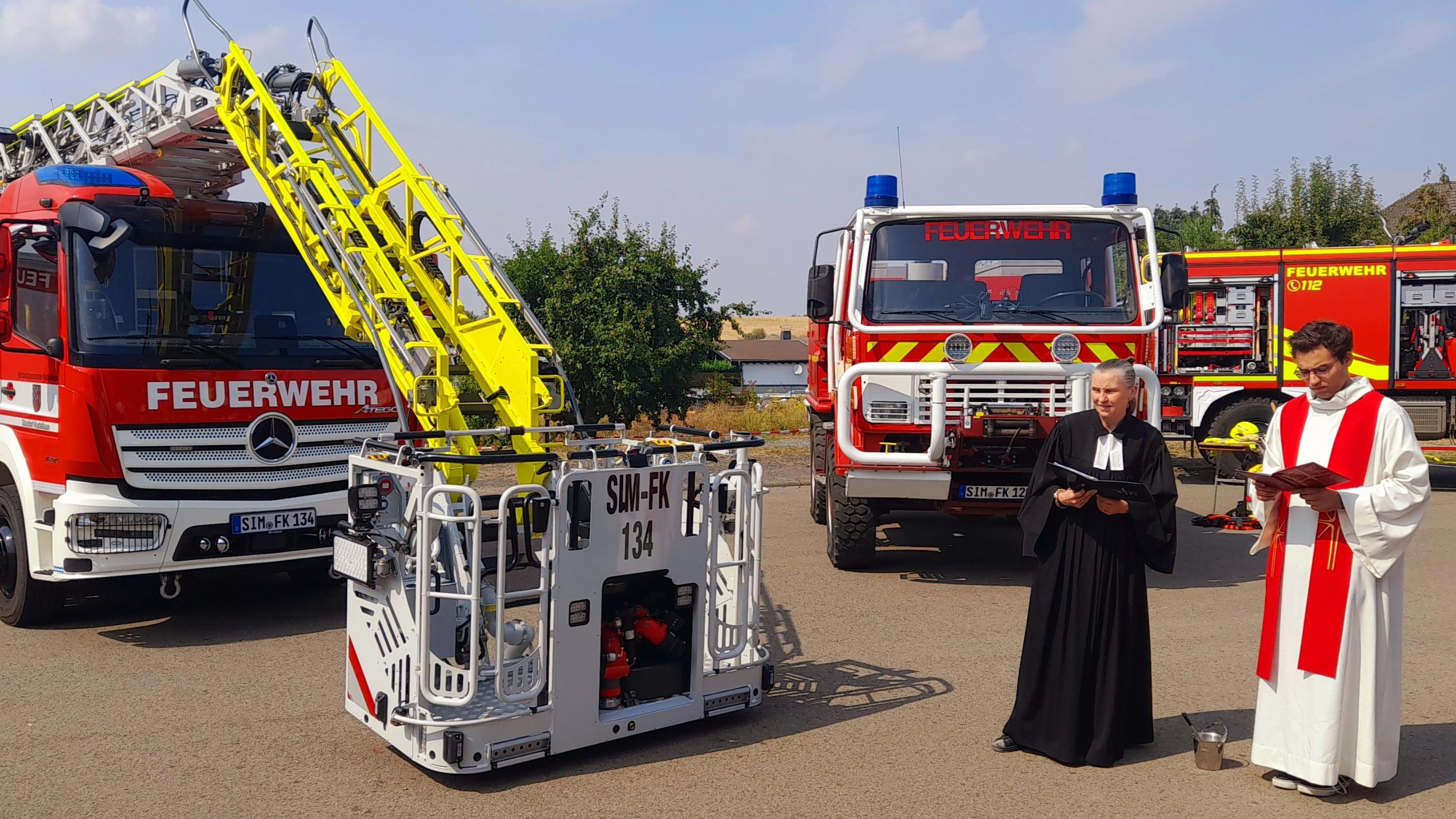 Kaplan Jager und Pfarrerin Floeth-Pulus vor den beiden Feuerwehrfahrzeugen