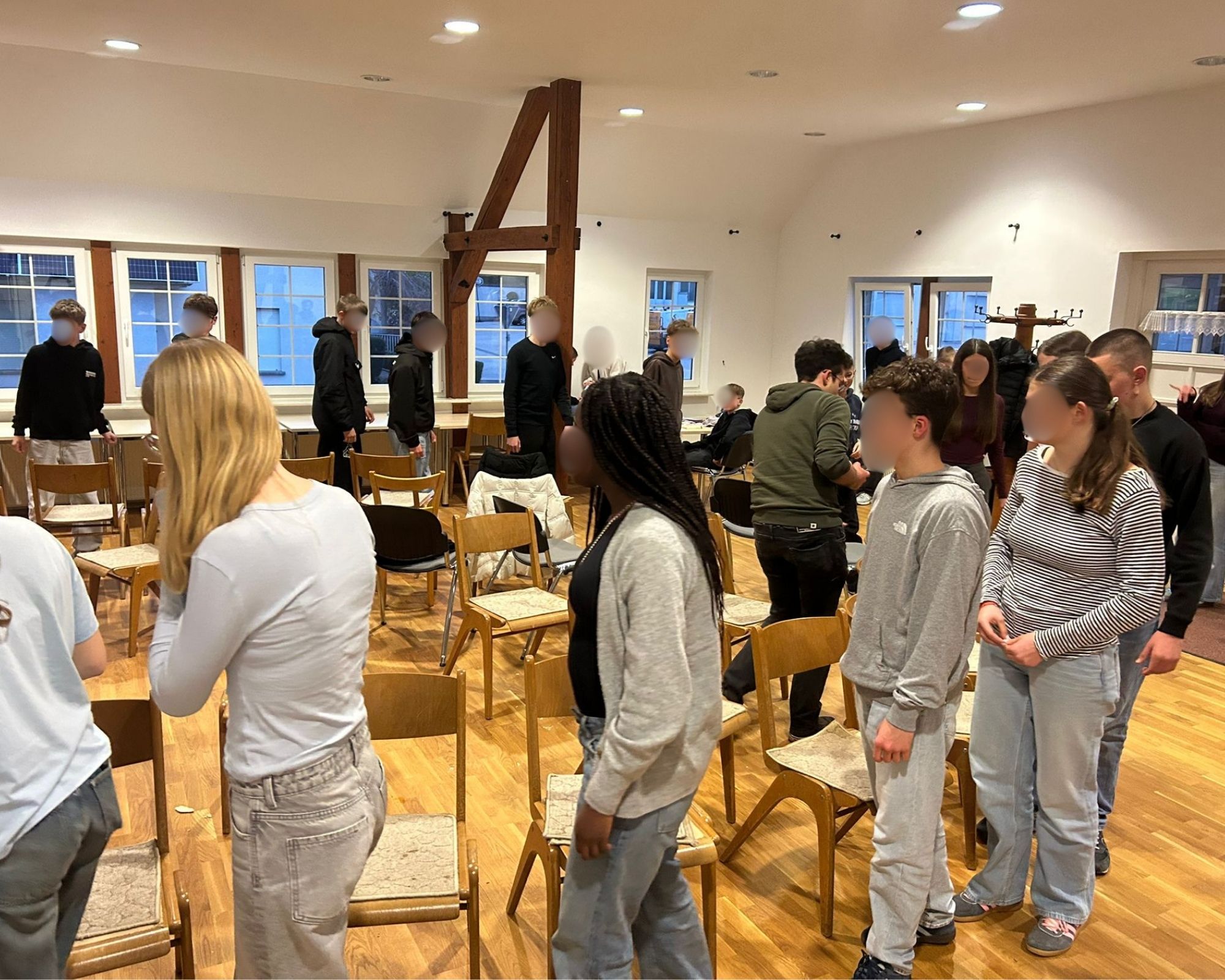 Junge Menschen gehen um einen Kreis aus Stühlen