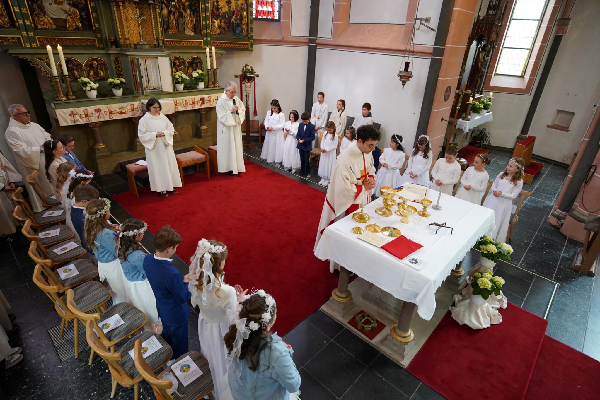 Kinder empfangen im Altarraum die erste heilige Kommunion.