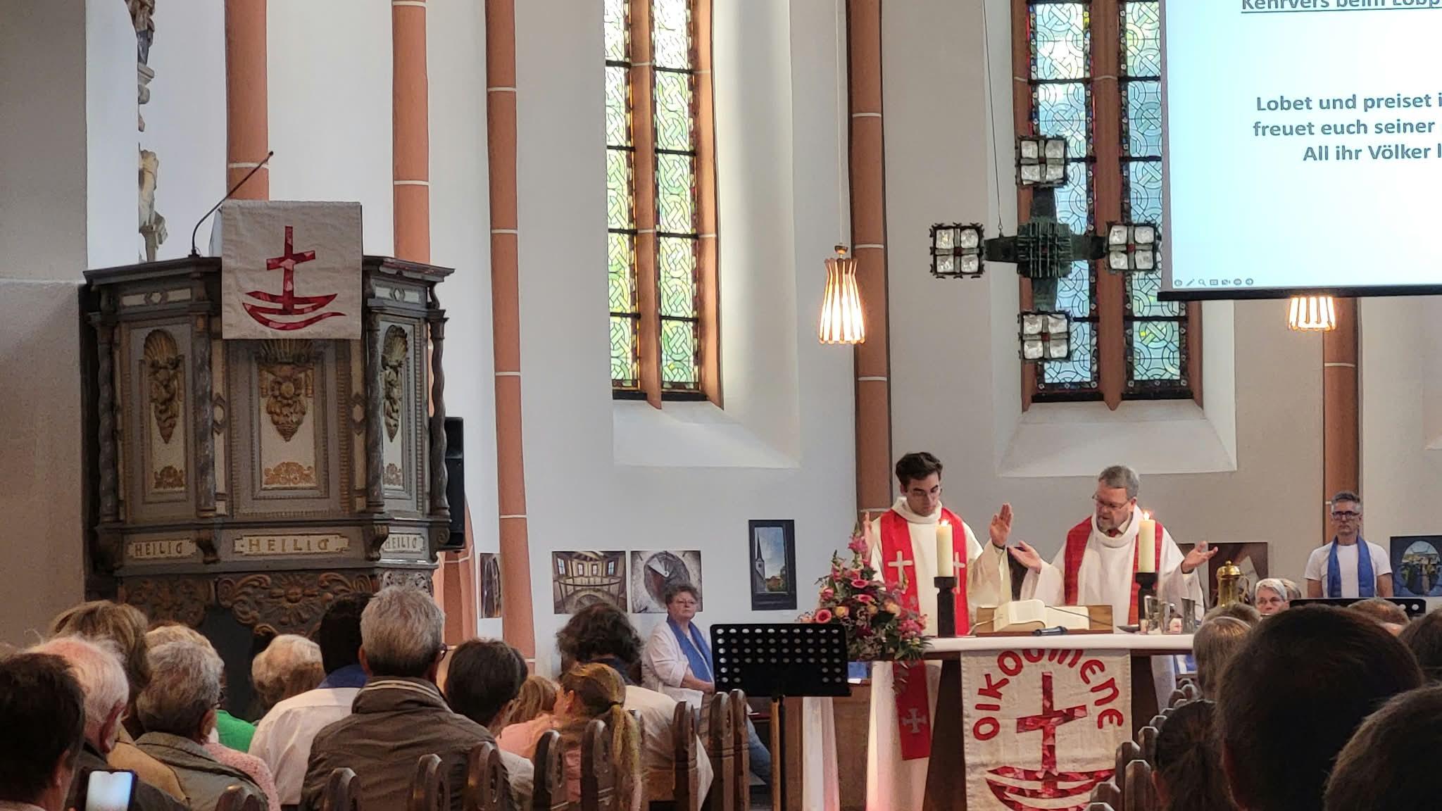 Zwei Geistliche stehen hinter einem Altar in einer evangelischen Kirche. Die Kircher ist gut besucht.