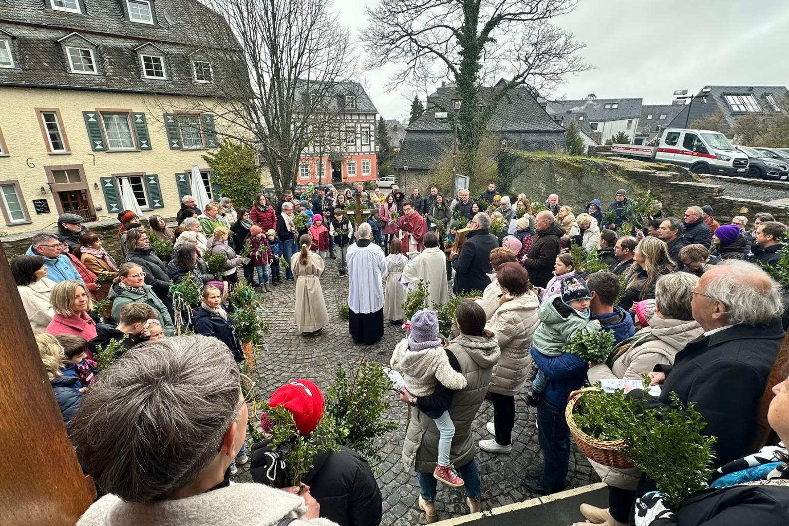 Die Gemeinde ist zur Palmweihe auf dem Kirchenvorplatz versammelt.