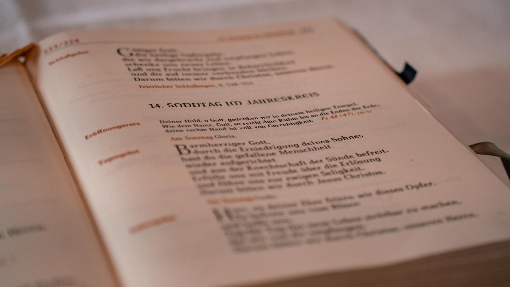 Nahaufnahme eines geöffneten Messbuchs mit liturgischen Texten. Die Seite zeigt Gebete und Lesungen für den Gottesdienst, während der Hintergrund unscharf bleibt.