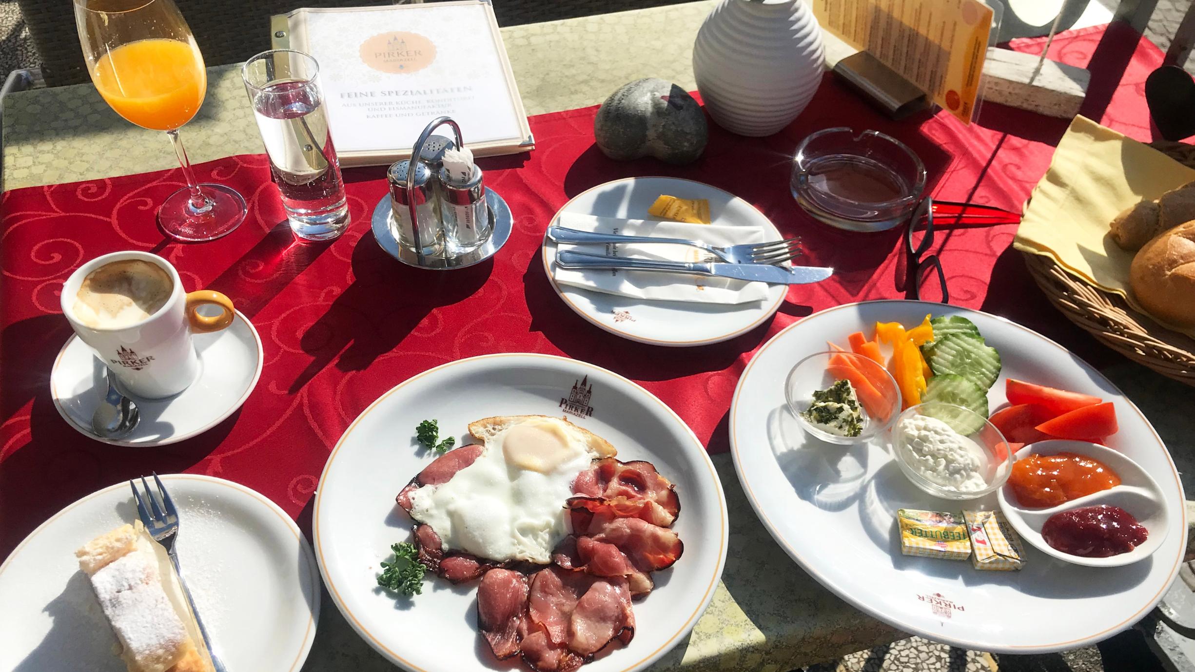 mehrere Frühstücksteller mit Speisen , dazu Saftglas und Kaffeetasse