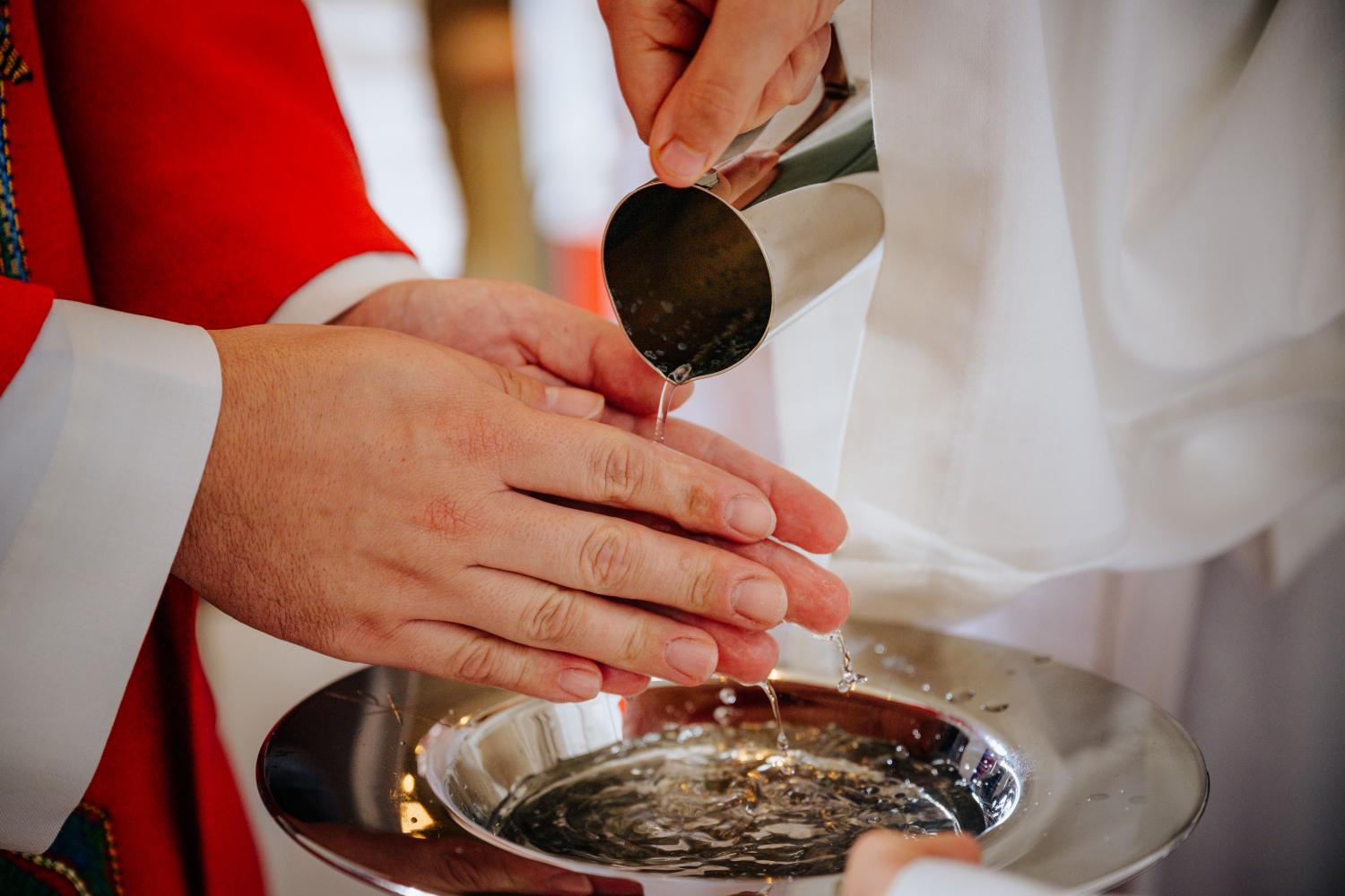 Ministranten waschen Priester im Gottesdienst die Hände.